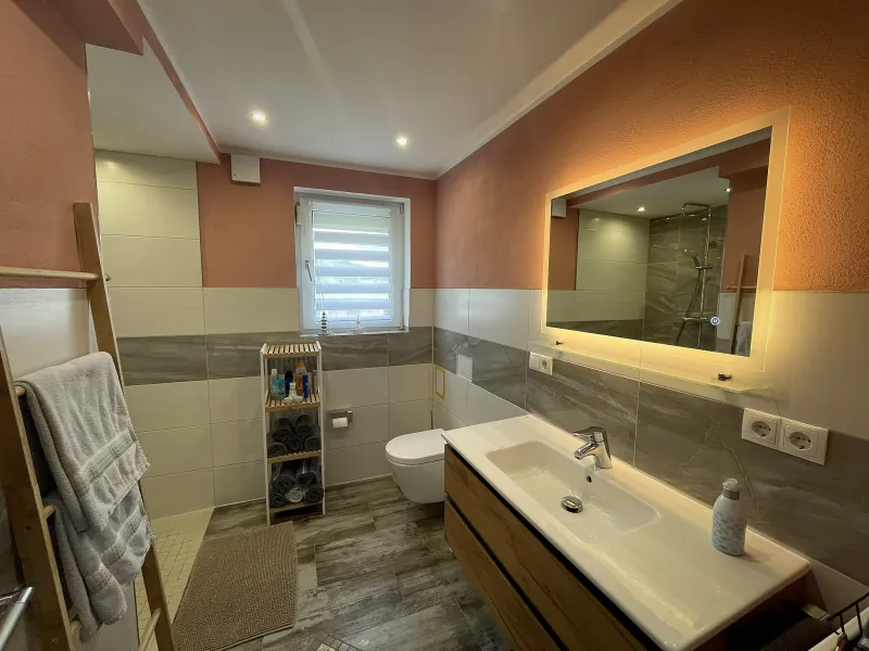 Badezimmer der Ferienwohnung Liesel mit beleuchtetem Spiegel und Waschtisch