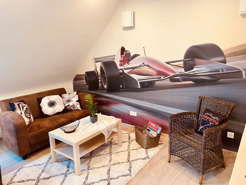 Wohnbereich der Ferienwohnung Sofia im Dachgeschoss: Sofa und Rennwagen-Wandbild unter der Dachschräge